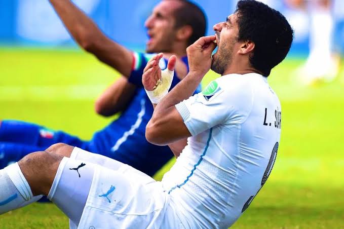 Luis Suarez checking his teeth after it has landed on Giorgio Chiellini's shoulder 