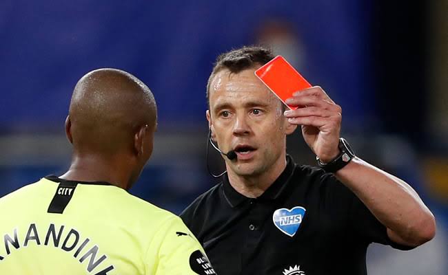 A Premier League referee applying a red card rule on a player. 