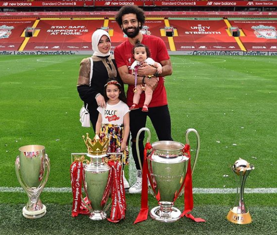 Mohamed Salah with his wife Maggi, his daughters Makka and Kayan, and the trophies he has won with Liverpool football club.