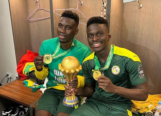 Ismaila Sarr and his Senegalese teammate Dieng Ahmadou Bamba posing with the AFCON trophy. 
