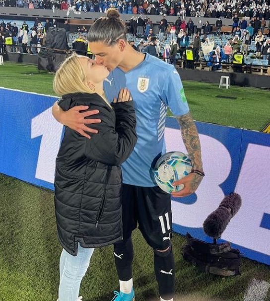 Darwin Nunez and his girlfriend Lorena Manas kissing inside a stadium after an international game.