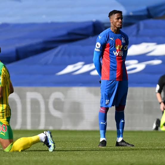 Wilfred Zaha standing whilst the Anti-racism gesture was ongoing. 