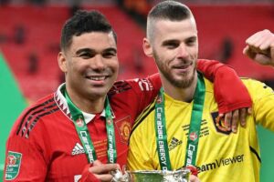 Manchester United players Casemiro and David De Gea holding the Carabao Cup trophy