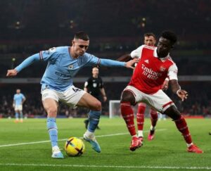 Arsenal's Bukayo Saka trying to get the ball away from Manchester City Phil Foden